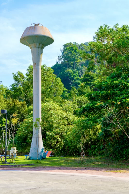 Винтажная водонапорная башня в густом зелёном лесу