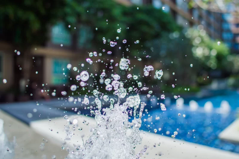 Замерзшие капли воды брызгают в яркой сцене у бассейна