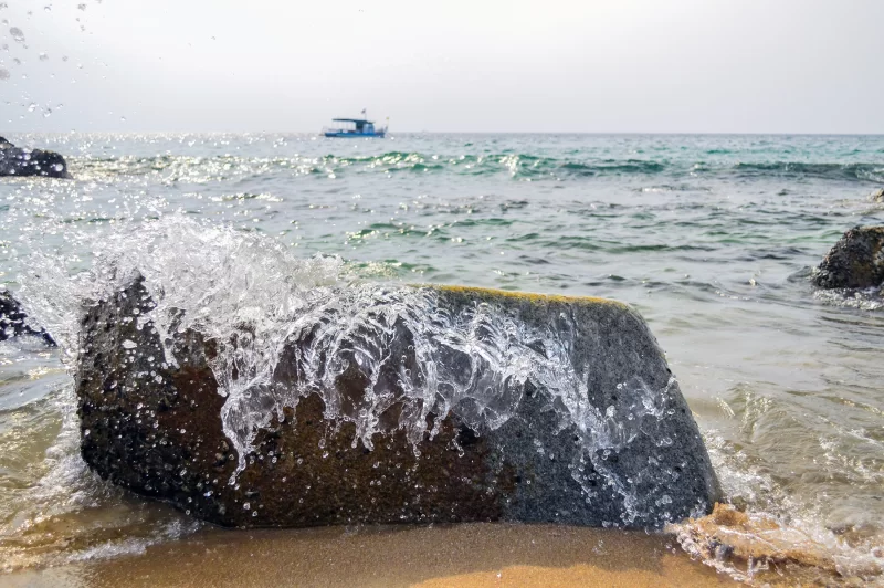 Волны разбиваются о скалу на пляже