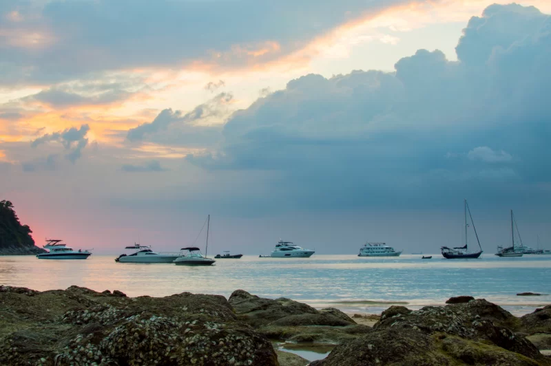 Закат над скалистым пляжем с яхтами