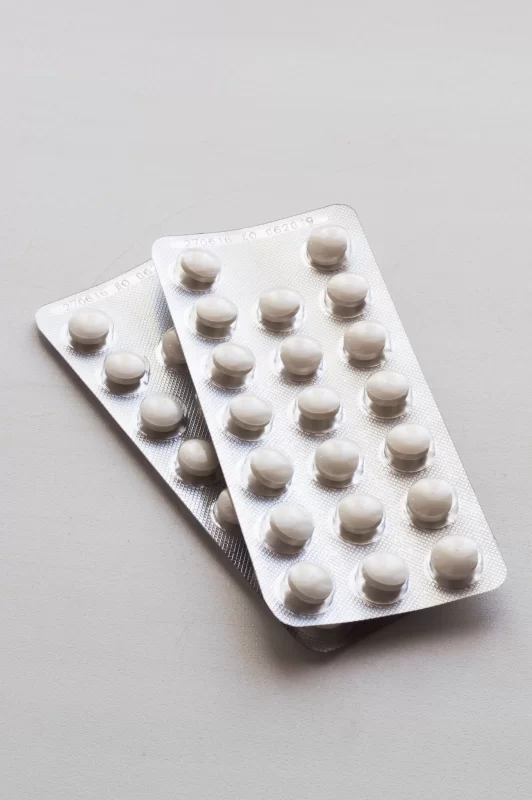 Две упаковки таблеток в блистерах на сером фоне