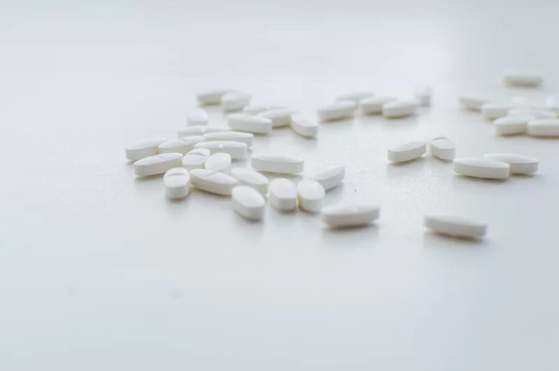 White pills scattered on a white background