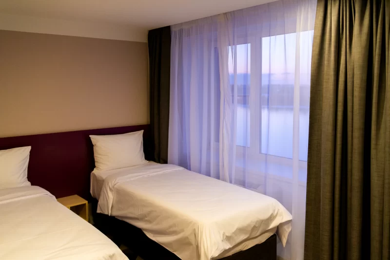 Уютный гостиничный номер с двумя кроватями и видом из окна