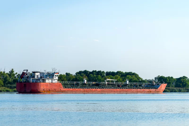 Красный танкер нефти на реке