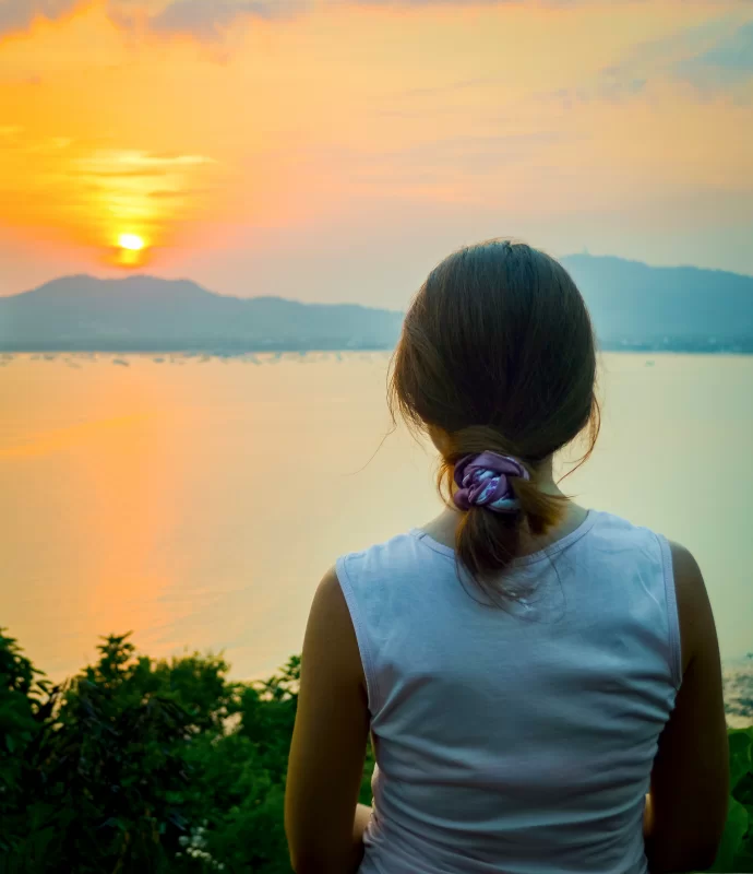Young woman watching sunset over lake