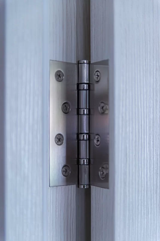 Металлическая петля на двери с текстурой дерева