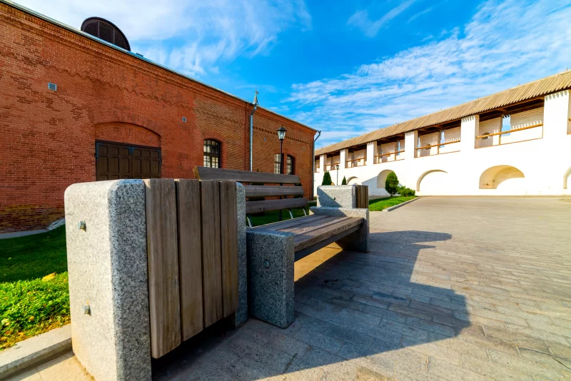 Уличный мусорный бак, декорированный камнем и деревянными досками.