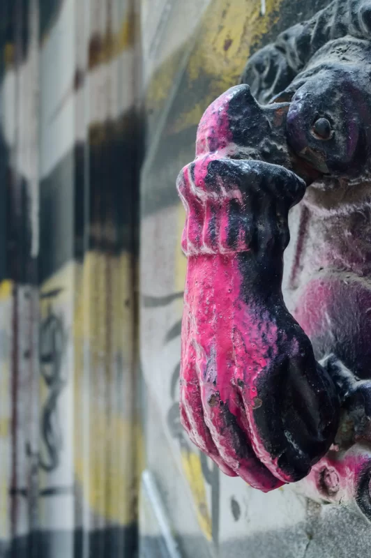 Рука грифона с ярким розовым покрытием на фоне граффити