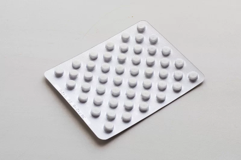 Blister pack with white pills on a gray background