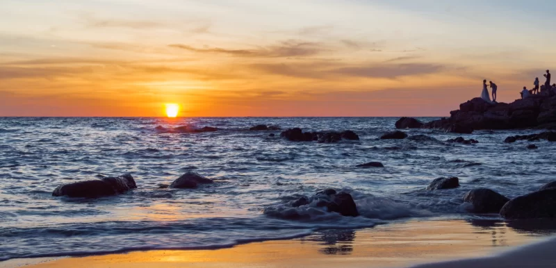 Закат над тропическим пляжем с силуэтами