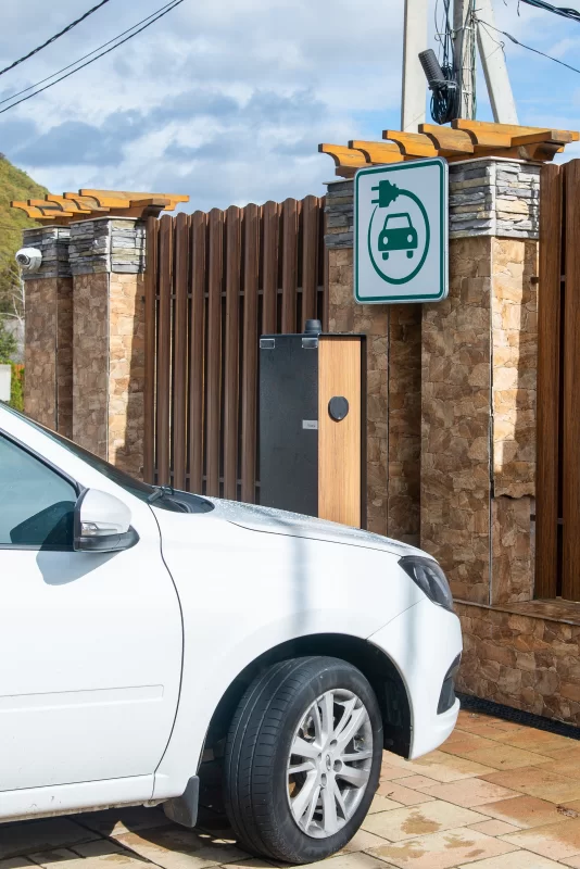 Электромобиль у зарядной станции в современном загородном дворе