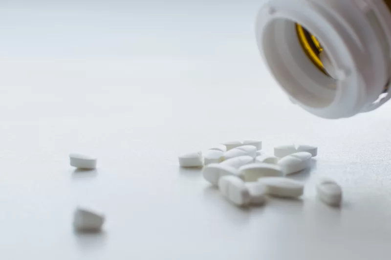 White pills spilling from a bottle, close-up