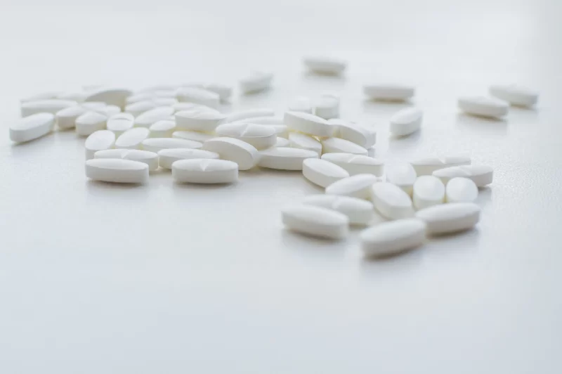 Белые таблетки, разбросанные на светлом фоне