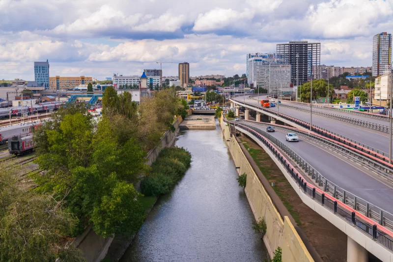 Городской ручей с автотрассой и современными зданиями