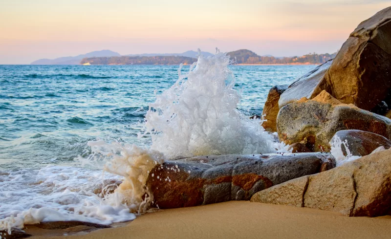 Волна разбивается о скалы на закате