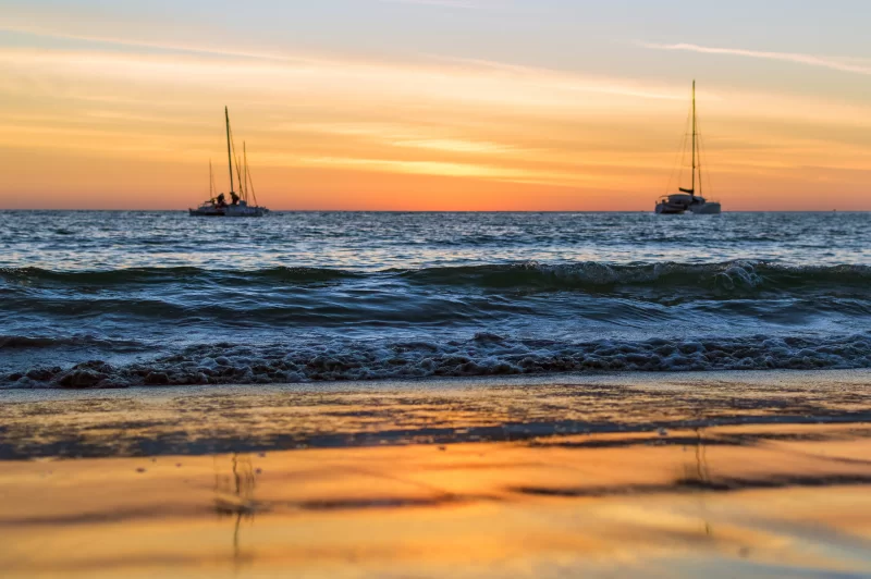 Sailing boats at sunset on the beach
