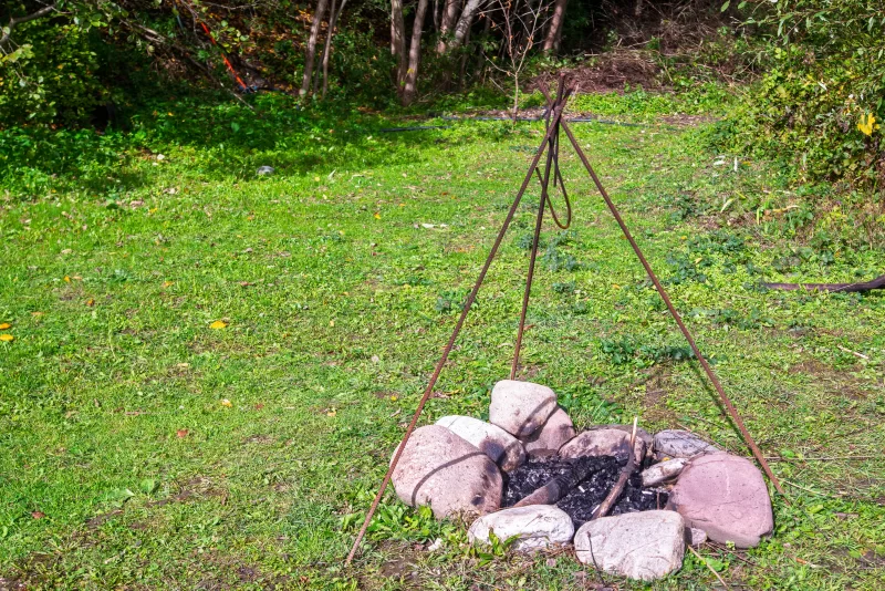 Костер в лесу: каменная огневая зона с металлическим каркасом для приготовления пищи