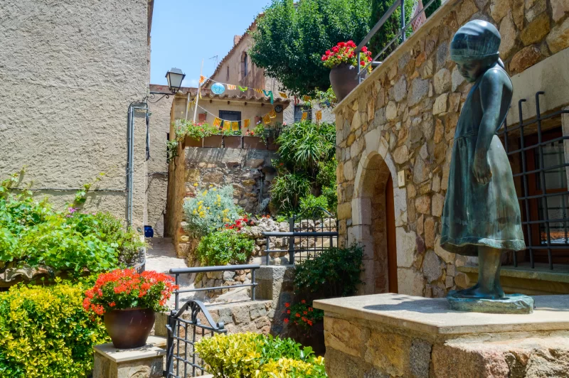 Маленькая девочка на статуе в узкой улице старого города