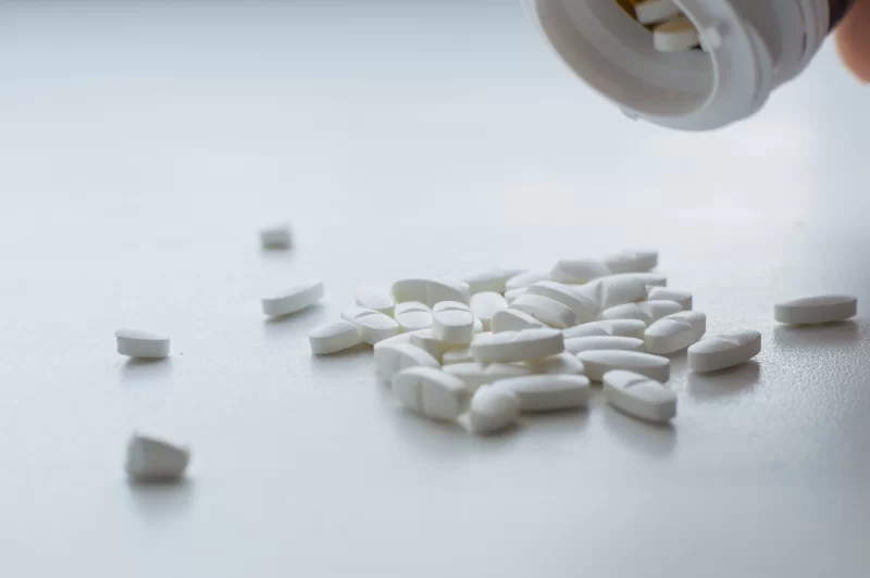 White pills spilling out of a container onto a surface