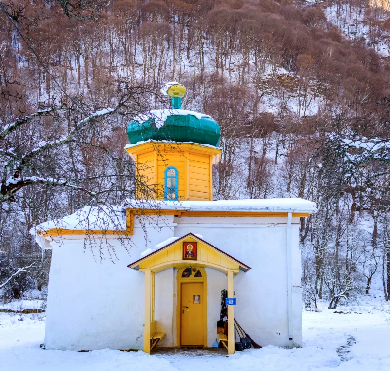 Зимний закат над живописной русской церковью в заснеженном лесу