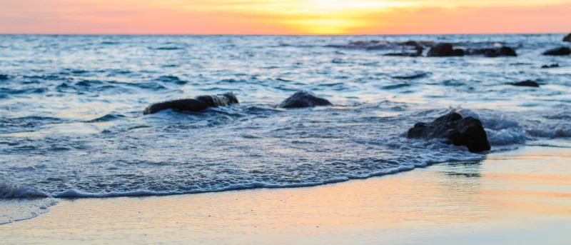 Закат над волнами океана на песчаном пляже