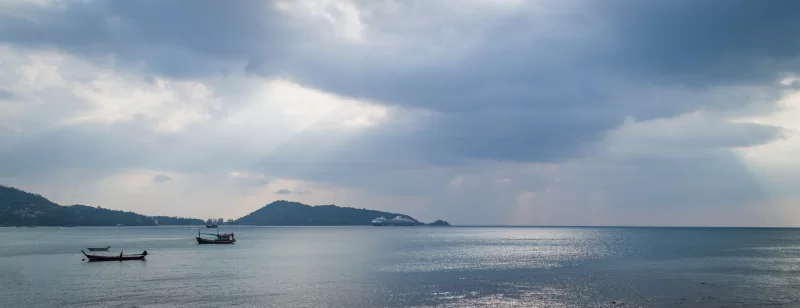 Sunlight piercing through storm clouds over tranquil sea