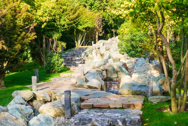 Японский сад с каменной дорожкой и водопадом в солнечный день