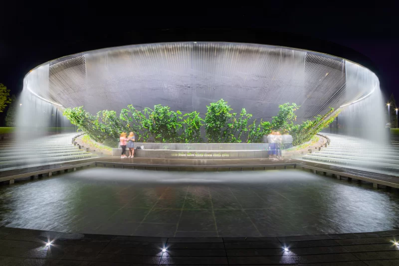 Современный архитектурный фонтан с каскадом воды ночью