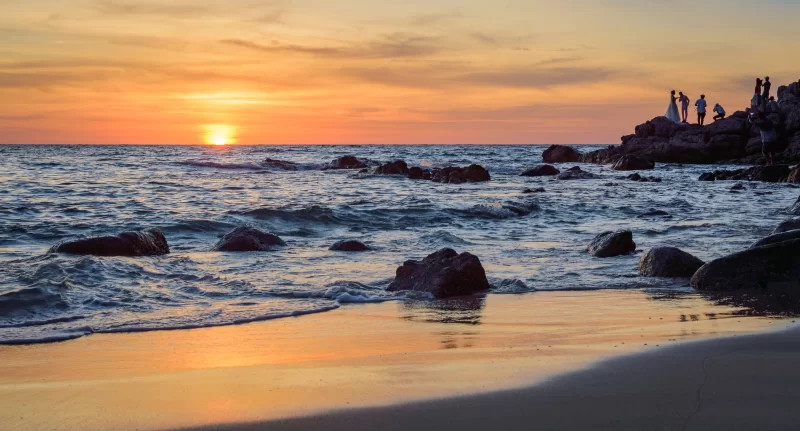 Закат над тропическим пляжем с силуэтами