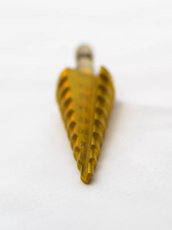 Золотая ступенчатая сверло на белом фоне