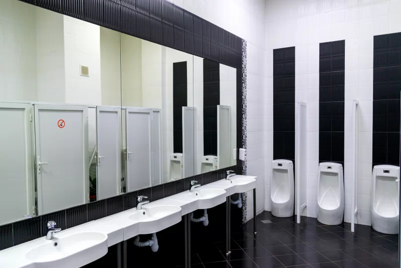 Современный мужской туалет с раковинами и писсуарами в черно-белой гамме