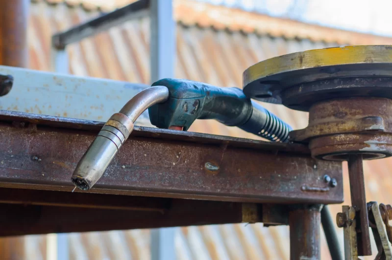 Сварочная горелка на фоне промышленного объекта