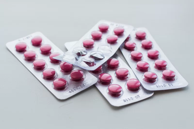 Блистеры с розовыми таблетками на сером фоне