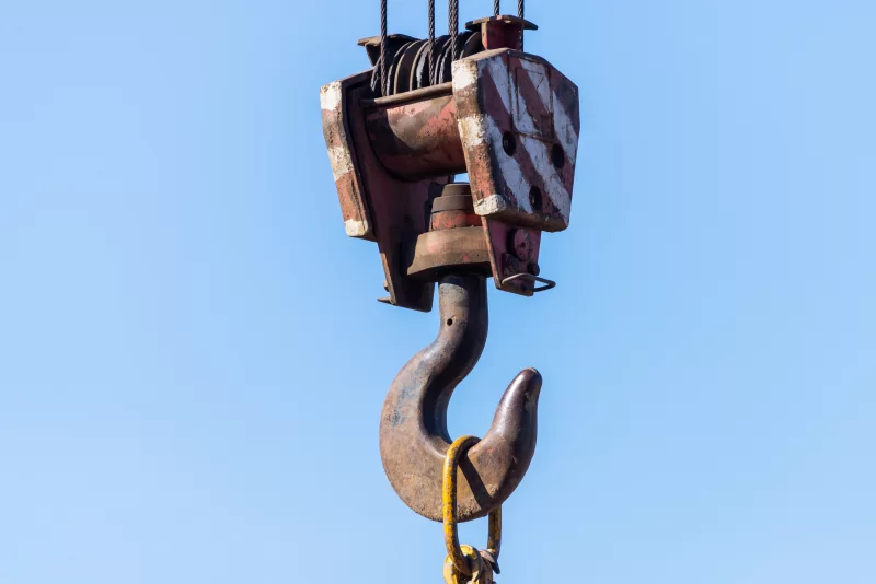 Крупный план крюка грузоподъемного крана на фоне ясного голубого неба