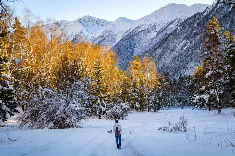 Winter walk in snowy mountains: girl explores a snow-covered path