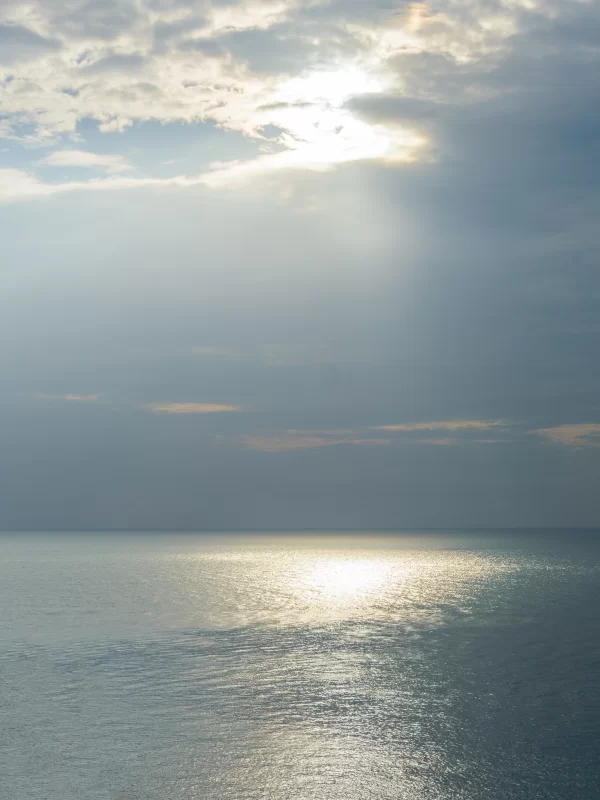 Солнечный свет сквозь штормовые облака над спокойным океаном