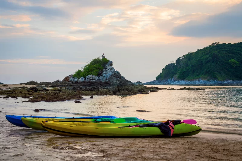Цветные каяки на пляже во время заката