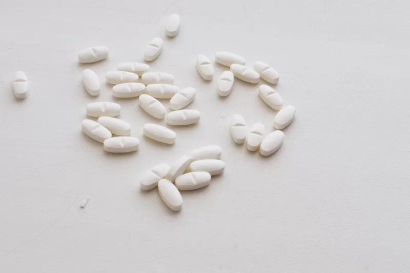 Белые овальные таблетки, разбросанные на светлом фоне