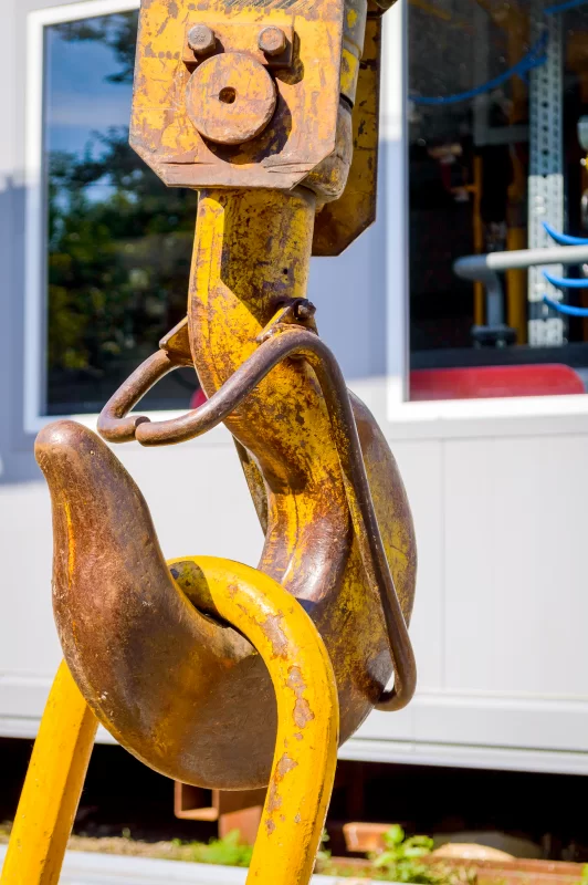 Крупный план ржавого желтого грузового крюка крана на фоне строительной площадки