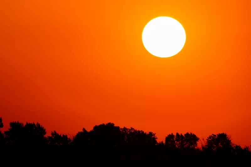 Яркое солнце на оранжевом небе с облаками во время заката