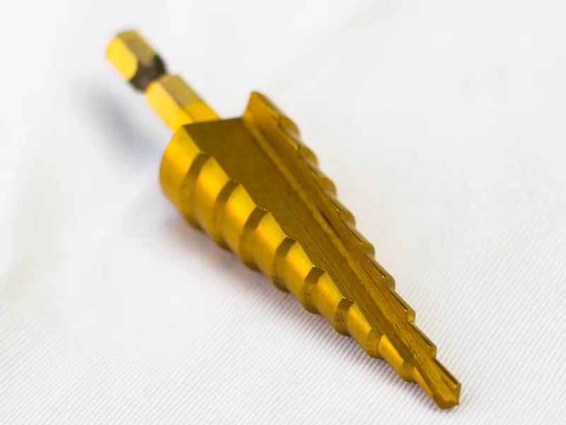 Золотая ступенчатая сверловая бита на белом фоне