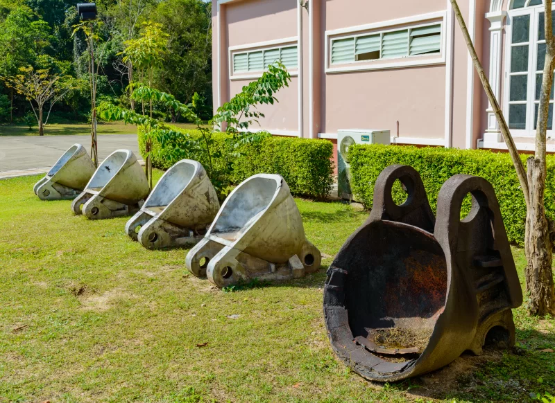 Ржавые баки для добычи руды на траве рядом с зданием