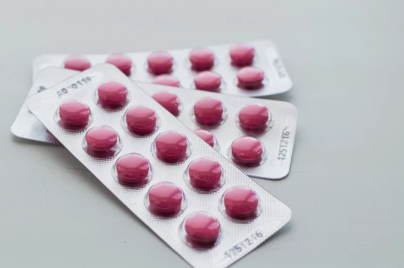 Две упаковки розовых таблеток в блистерах на светлом фоне