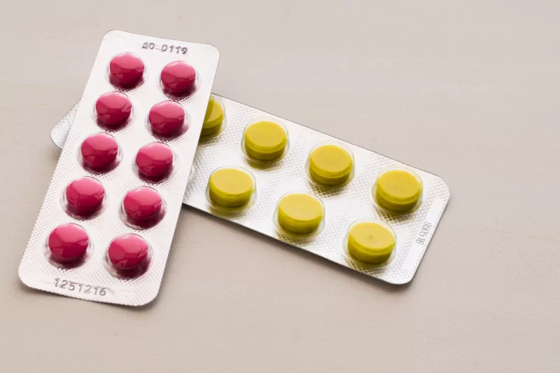 Two blister packs of pills: red and yellow