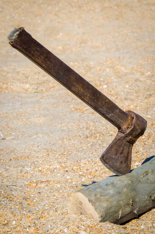 Старый ржавый топор на бревне на песчаном фоне