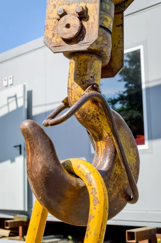 Мощный крюк строительного крана крупным планом на фоне голубого неба и здания