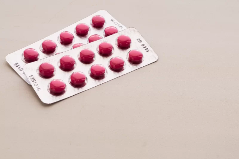 Две упаковки розовых таблеток в блистерах на светлом фоне