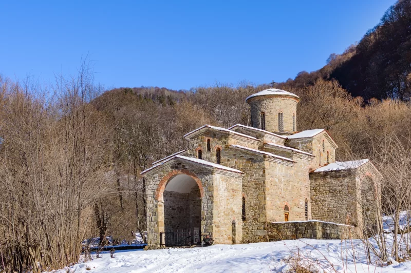 Зимний пейзаж с древним храмом в горах