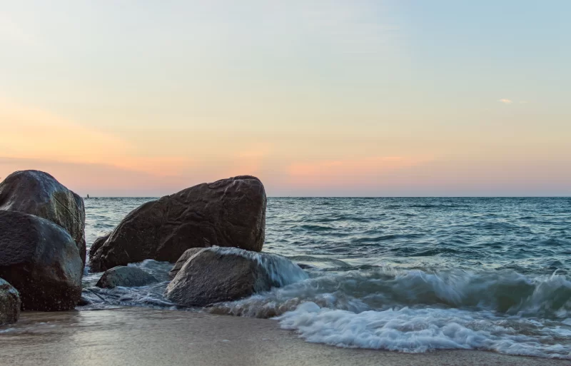 Волны океана разбиваются на скалистой берегу во время заката