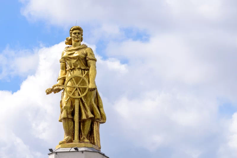 Золотая статуя на фоне облачного неба